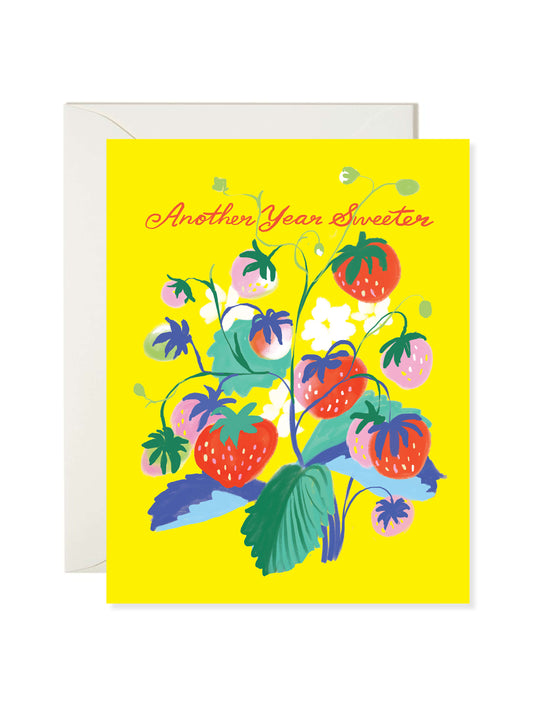 Illustrated birthday greeting card featuring a strawberry plant with red berries and flowers on a bright yellow background with “Another Year Sweeter” text by Karen Schipper.