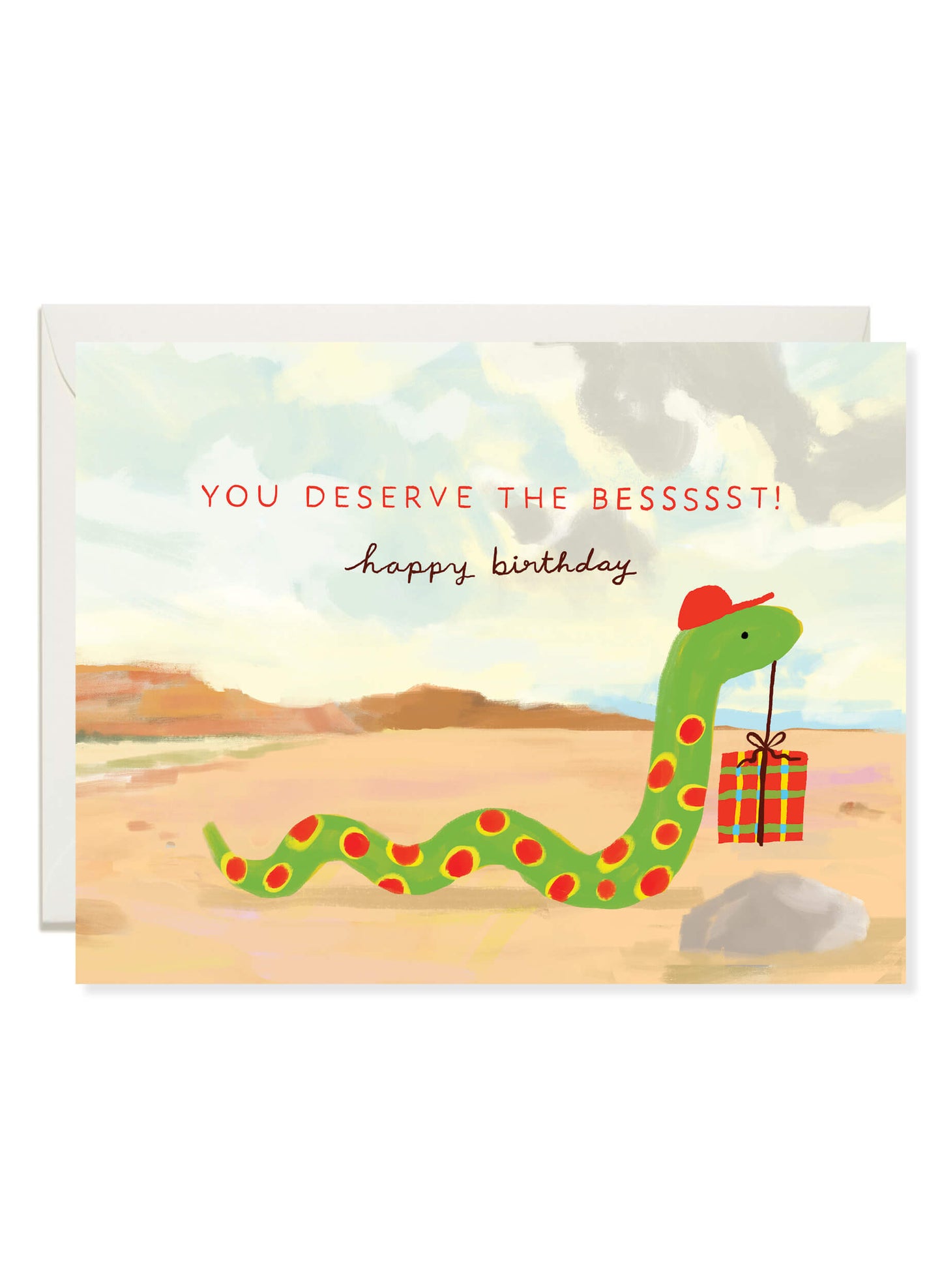 Snake Birthday card by Karen Schipper featuring a green snake in a red party hat holding a tiny wrapped gift in the desert.