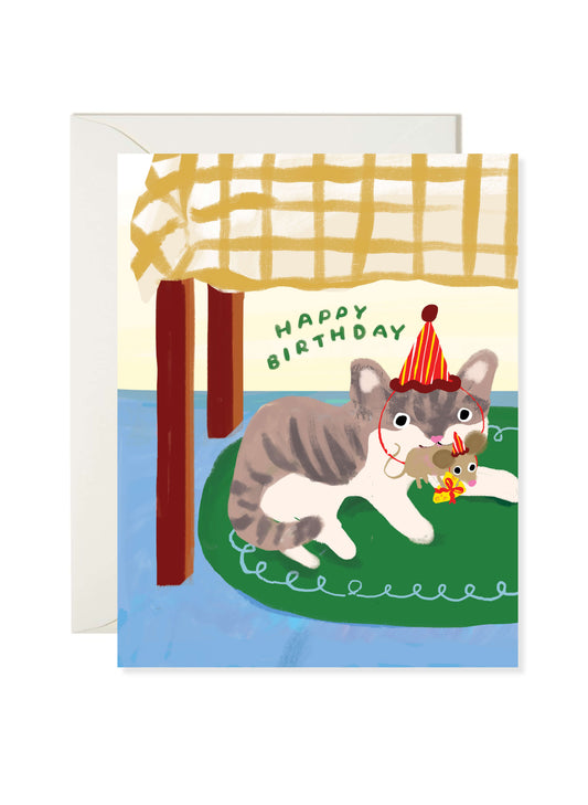 Cat Mouse Cheese Birthday Card by Karen Schipper featuring a gray and white cat under a table with a party-hat mouse holding cheese and a gift.