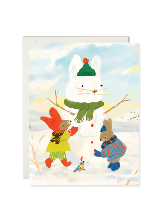 Snow Bunny card by Karen Schipper featuring a snowman, a white goose in a yellow coat, and a bunny in a blue plaid jacket in the snow.