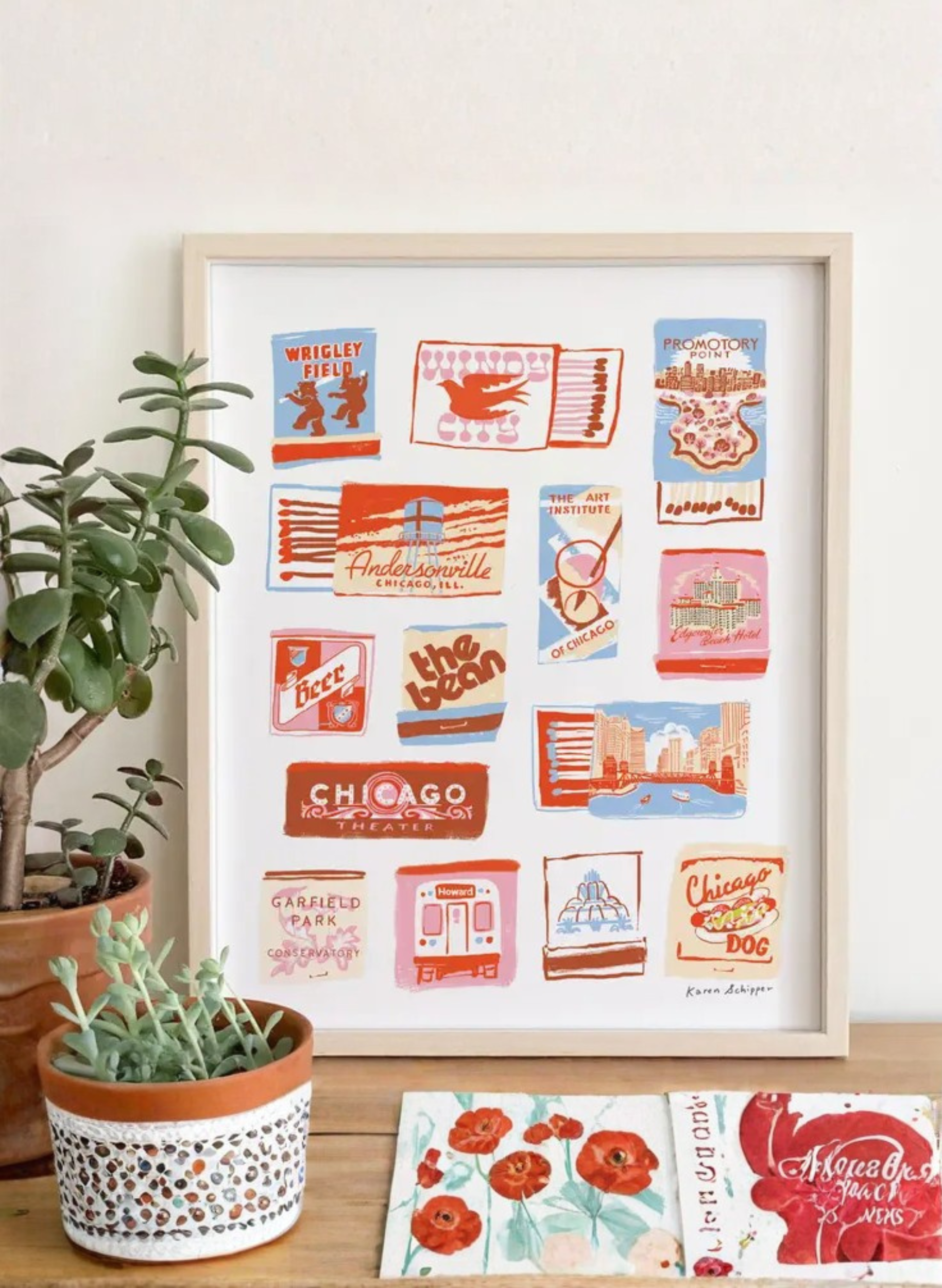 Framed Chicago Matchbook Art Print by Karen Schipper styled beside potted plants, featuring colorful Illinois matchbook-style city landmark artwork.