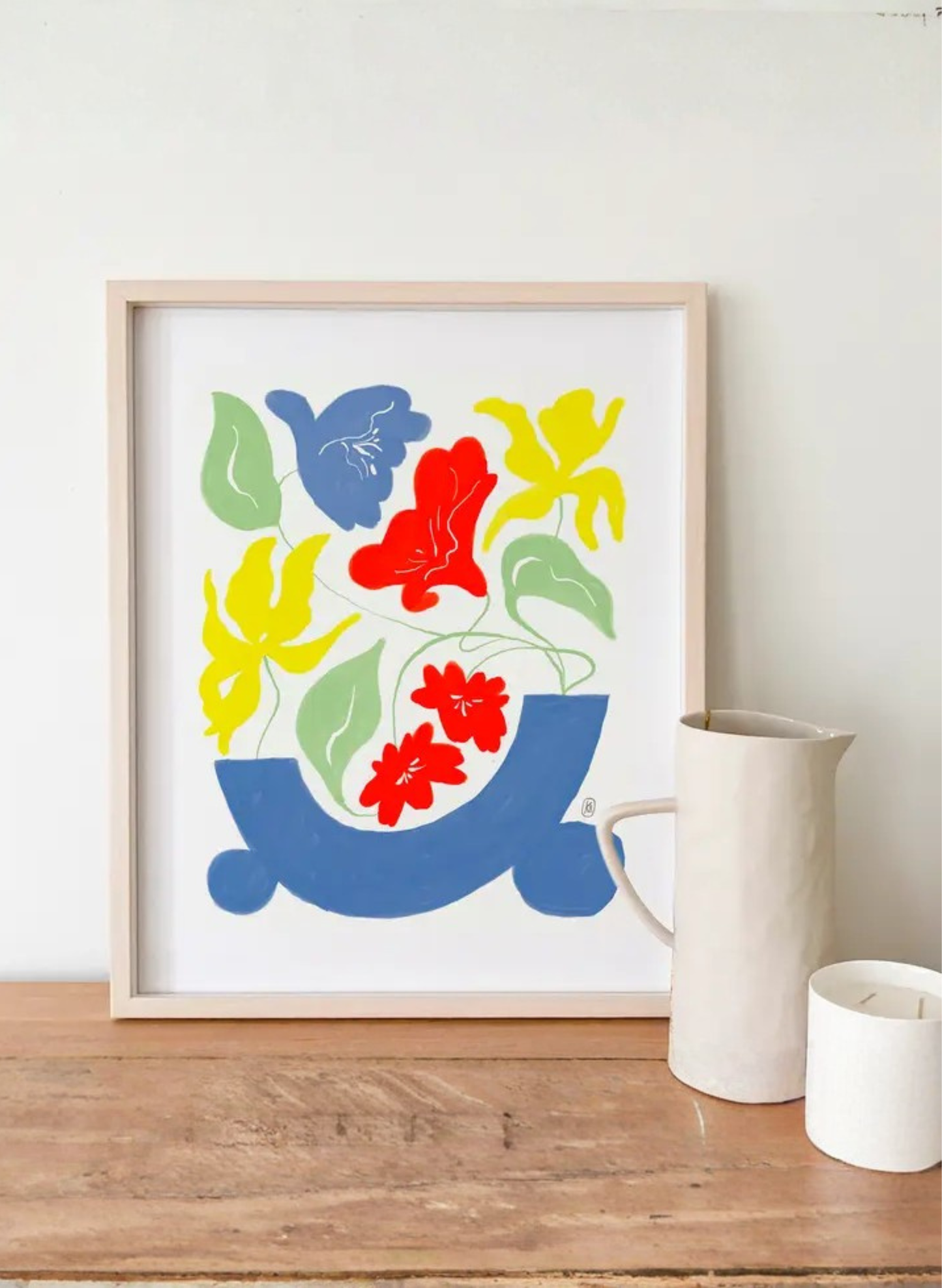 Framed Hyacinth Vase Art Print by Karen Schipper styled on a shelf with a white pitcher and candle, showing colorful floral wall art.