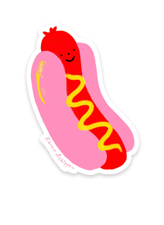 Hot Dog Sticker by Karen Schipper featuring a smiling red hot dog in a pink bun with a yellow mustard swirl in a simple, playful illustrated style.